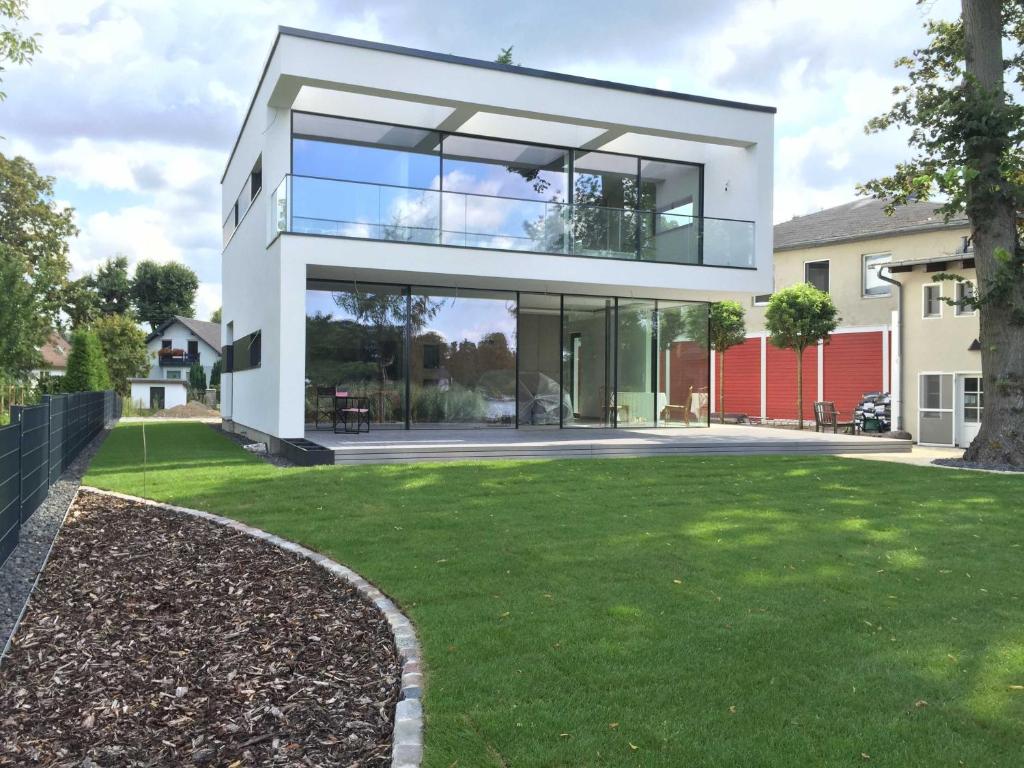 a modern house with glass windows and a yard at Exklusive Seevilla Berlin direkt am Zeuthener See in Berlin