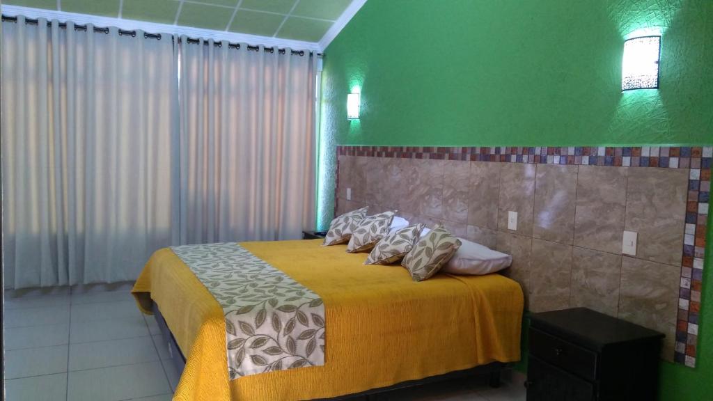 1 dormitorio con 1 cama con manta amarilla y almohadas en Villa Victoria Pirámides en San Martín de las Pirámides