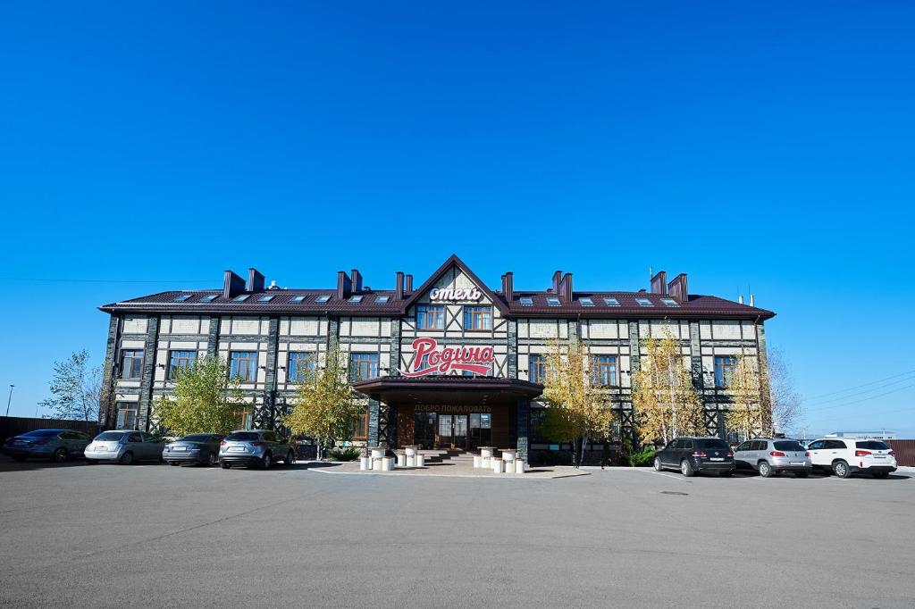 ein großes Gebäude mit Autos auf einem Parkplatz in der Unterkunft Rodina Hotel in Mayakovskogo