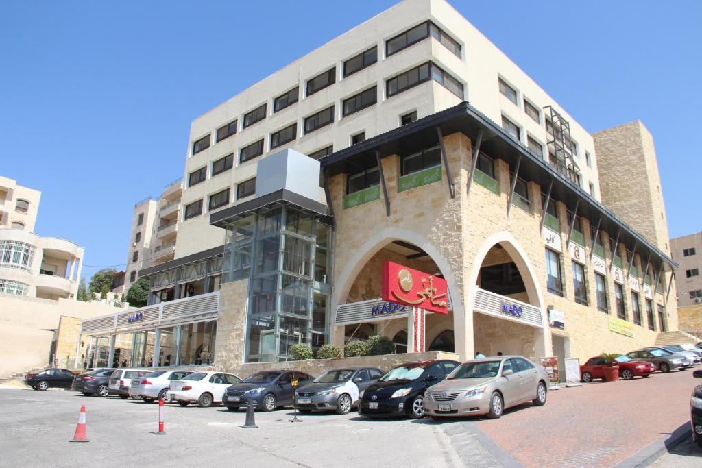 un grand bâtiment avec des voitures garées dans un parking dans l'établissement Saray Hotel Amman, à Amman