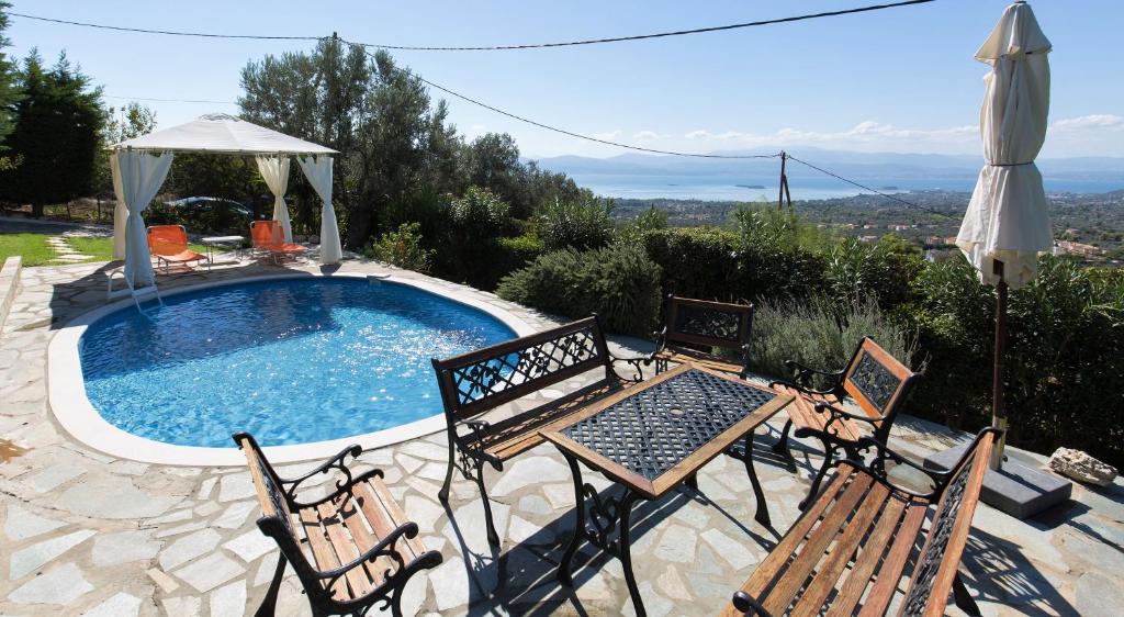 Villa Heavens Knights with private pool في Magoúla: مسبح وكراسي وطاولة ومظلة