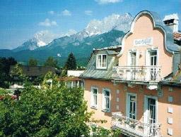 ein großes Backsteingebäude mit Bergen im Hintergrund in der Unterkunft Apartment Grattschlössl in Sankt Johann in Tirol