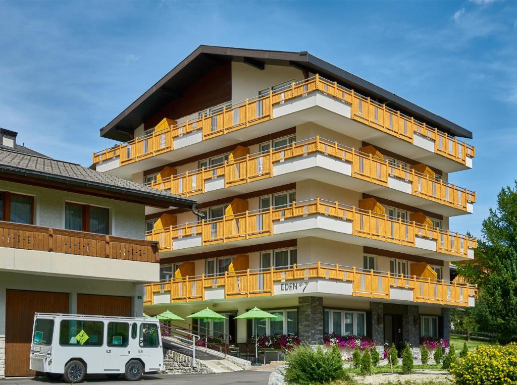 um edifício com uma carrinha branca estacionada em frente em Hotel Eden No. 7 em Saas-Fee