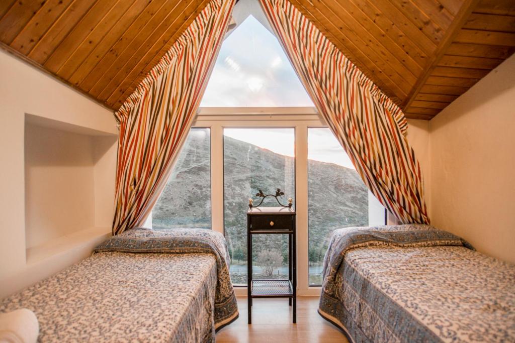 two beds in a room with a large window at Exclusivo DÚPLEX en la PLAZA in Sierra Nevada