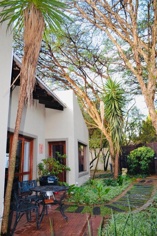 a patio with a table and palm trees in front of a house at Serendipity Cottage in Johannesburg