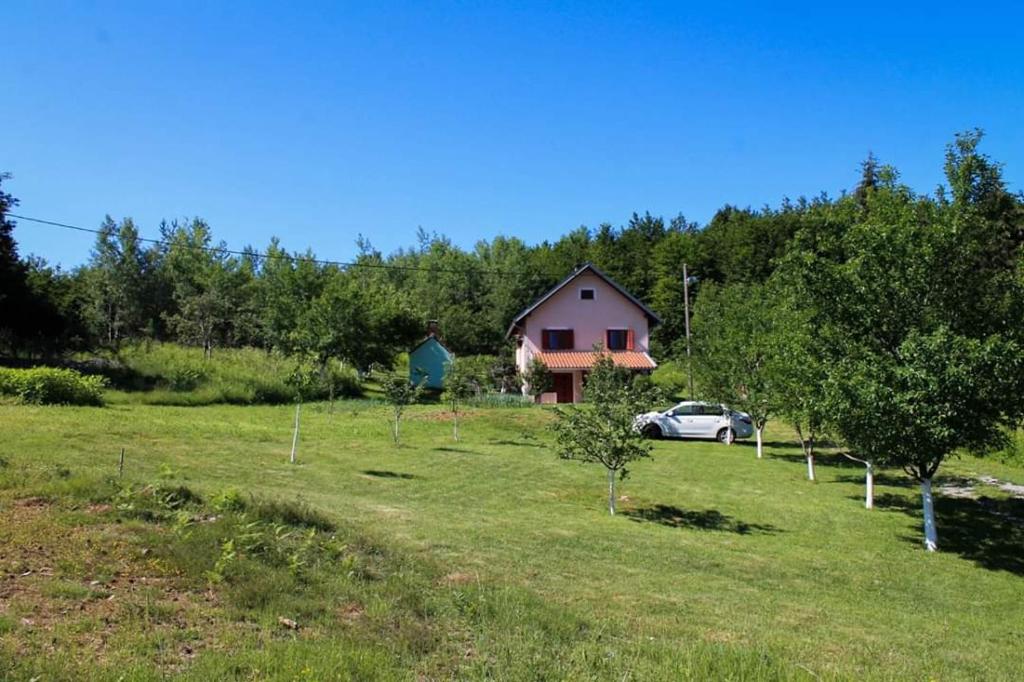una casa con un coche aparcado en un campo en Kuća u prirodi za odmor en Gračac