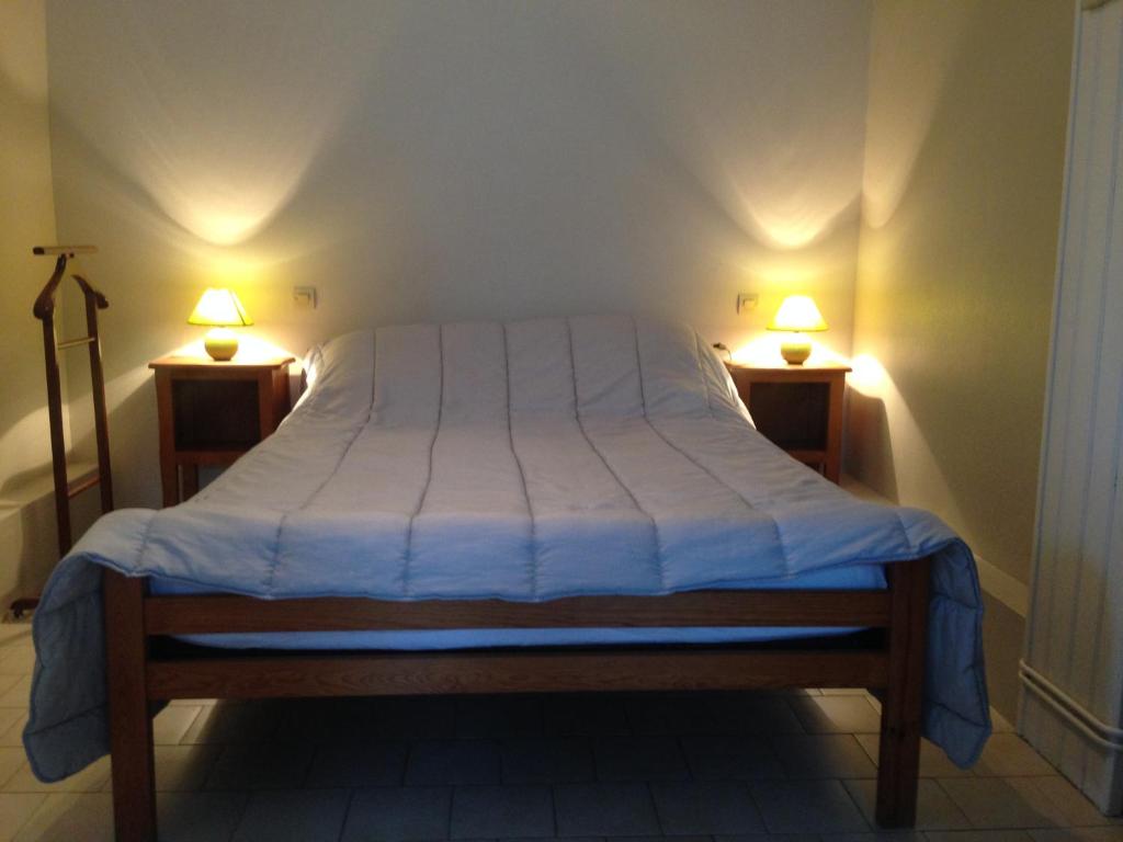 a bed in a room with two lamps on both sides at Résidence Les Plus Près in Jonzac
