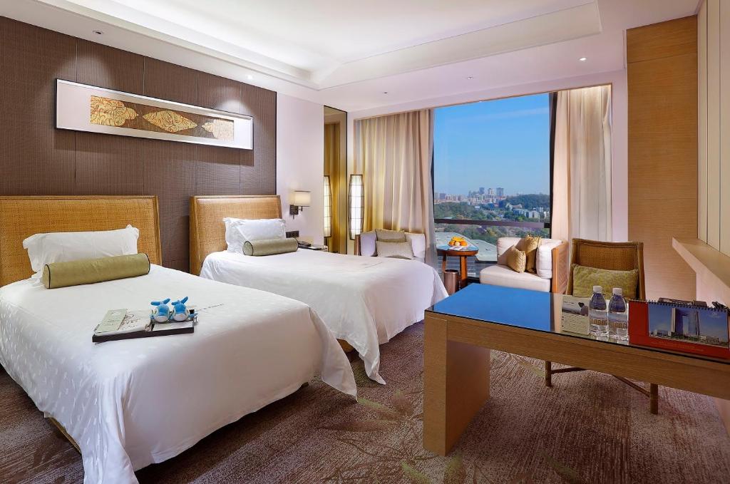 a hotel room with two beds and a desk at Dongguan Kande International Hotel in Dongguan