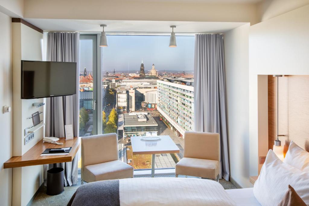 a hotel room with a bed and a view of a city at Pullman Dresden Newa in Dresden