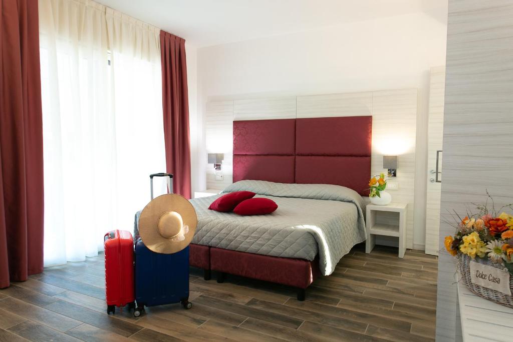 a bedroom with a bed with a red headboard and a suitcase at Guest House DOLCE LAGUNA 2 in Tessera