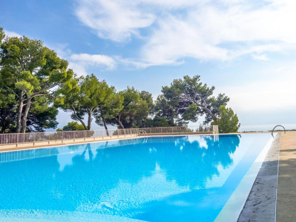 une piscine bleue avec des arbres en arrière-plan dans l'établissement Apartment Athéna Résidence-1 by Interhome, à Bandol