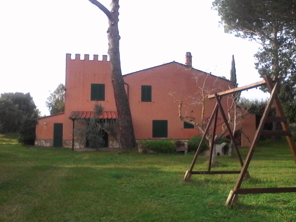une vieille maison avec une aire de jeux devant elle dans l'établissement Agriturismo La Torretta, à Castagneto Carducci