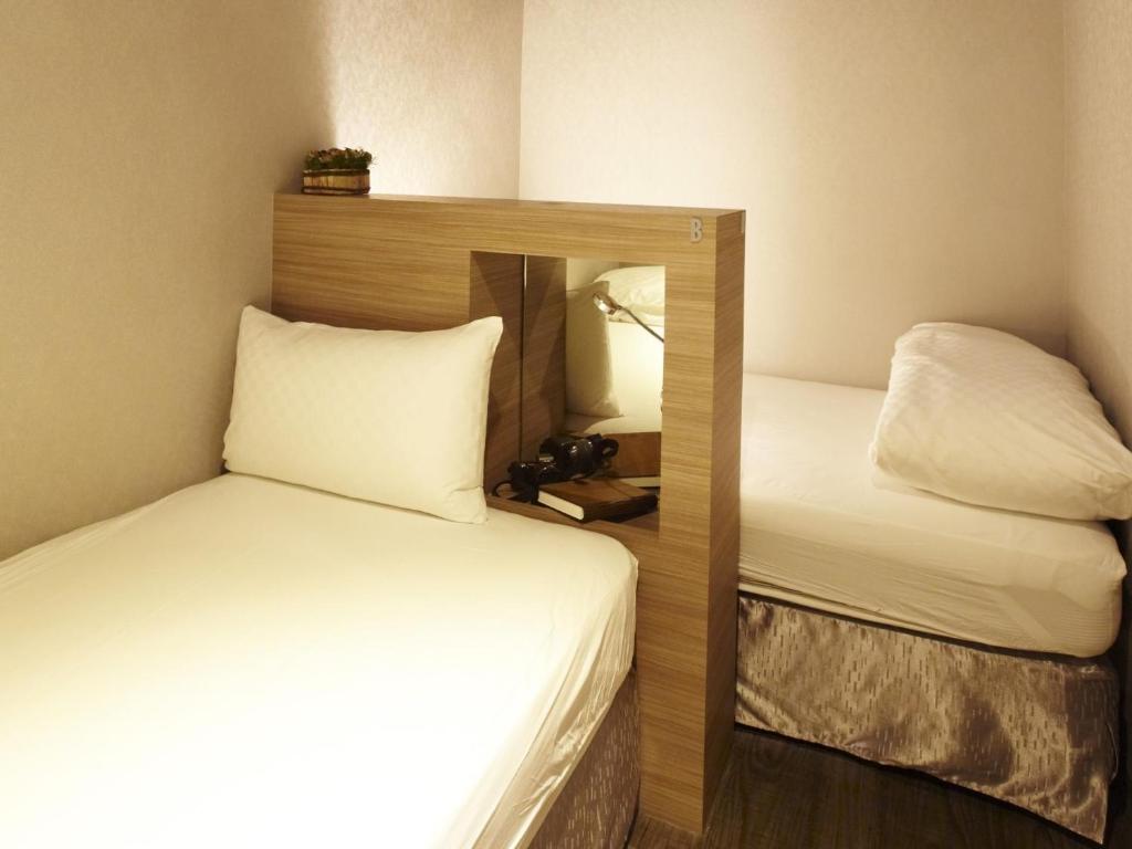a small room with two beds and a mirror at Main Inn Taipei in Taipei