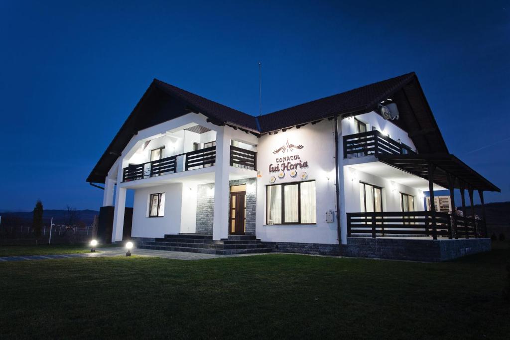 a white building with a black roof at night at Pensiunea Conacul lui Horia in Bistriţa