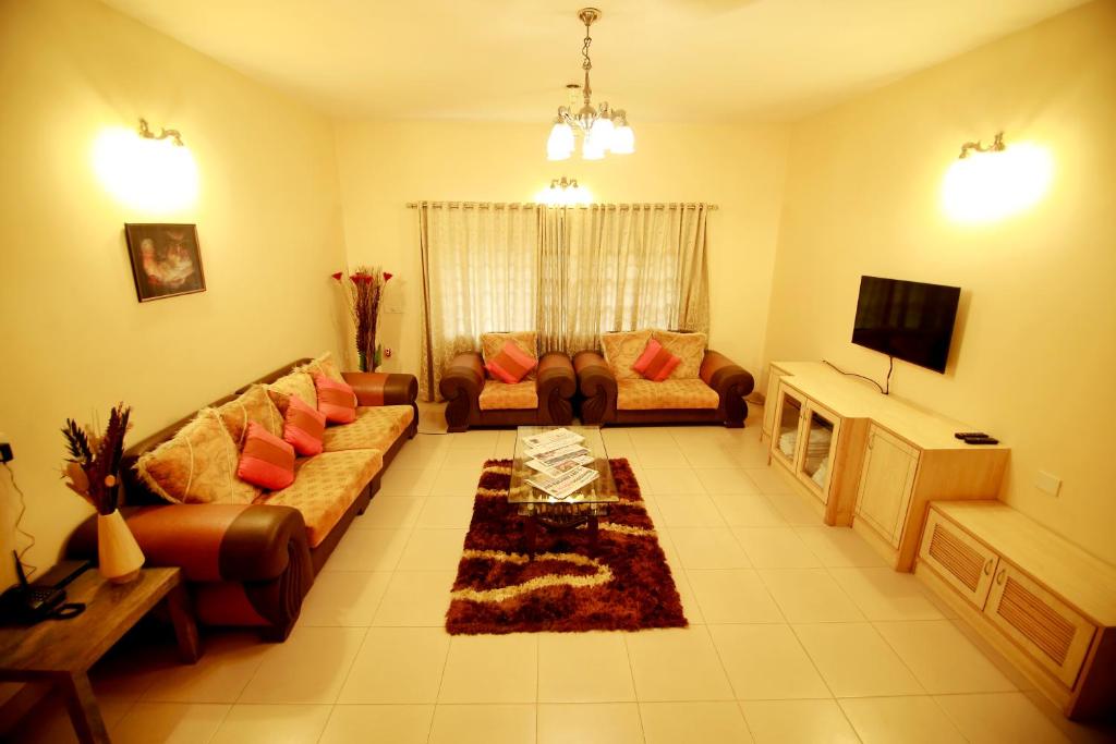 a living room with a couch and a tv at Falcon Suites Residency Road in Bangalore