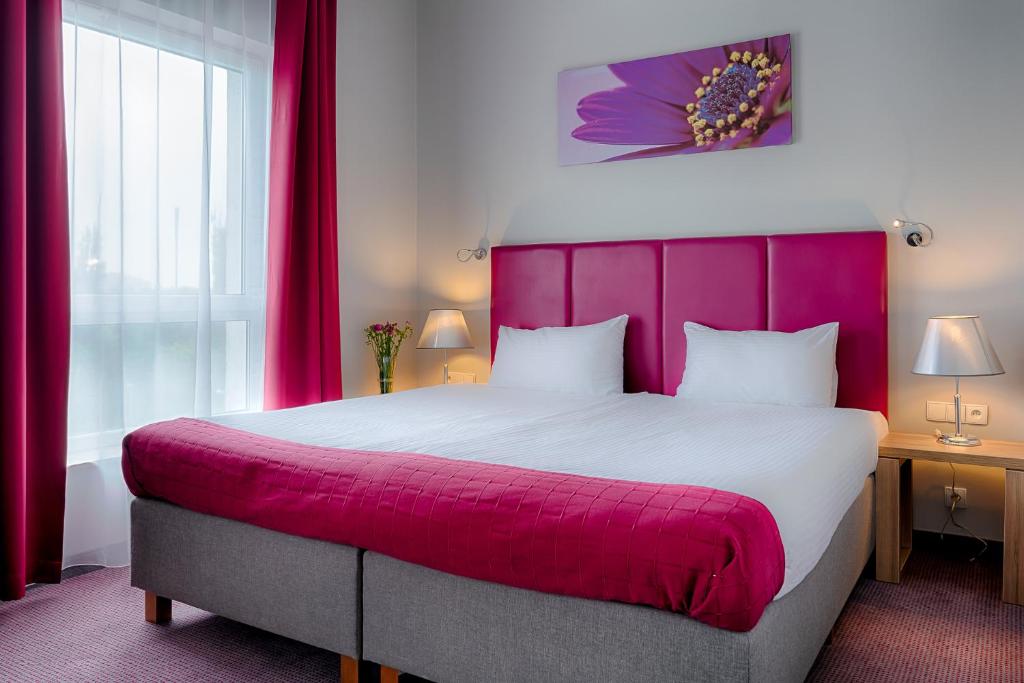 een slaapkamer met een groot bed met een roze hoofdeinde bij Focus Hotel Katowice Chorzów in Chorzów