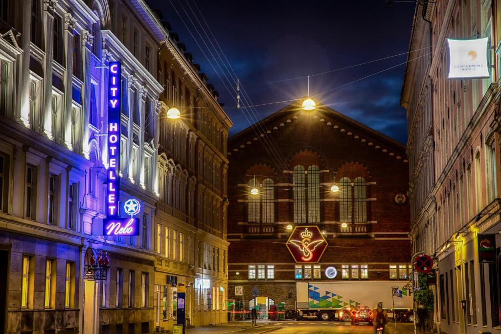 una via cittadina di notte con un edificio di City Hotel Nebo a Copenaghen