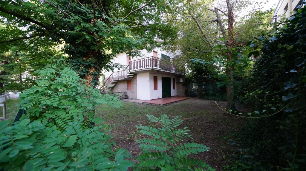 a house with a balcony and a yard with trees at Villetta 2C in Lido degli Estensi