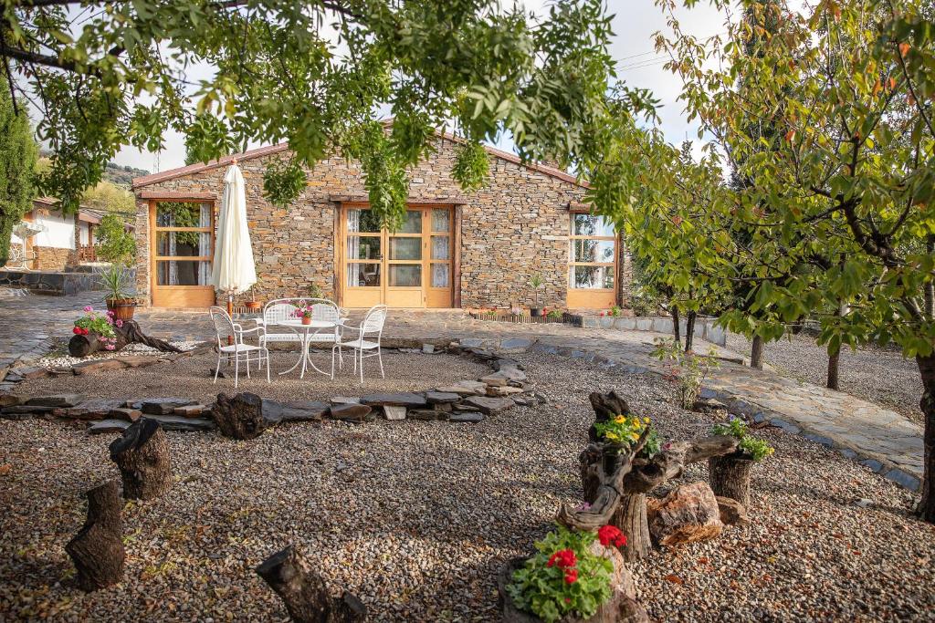 een stenen huis met een tafel en stoelen in een tuin bij El Paraje del Chef in Laroles