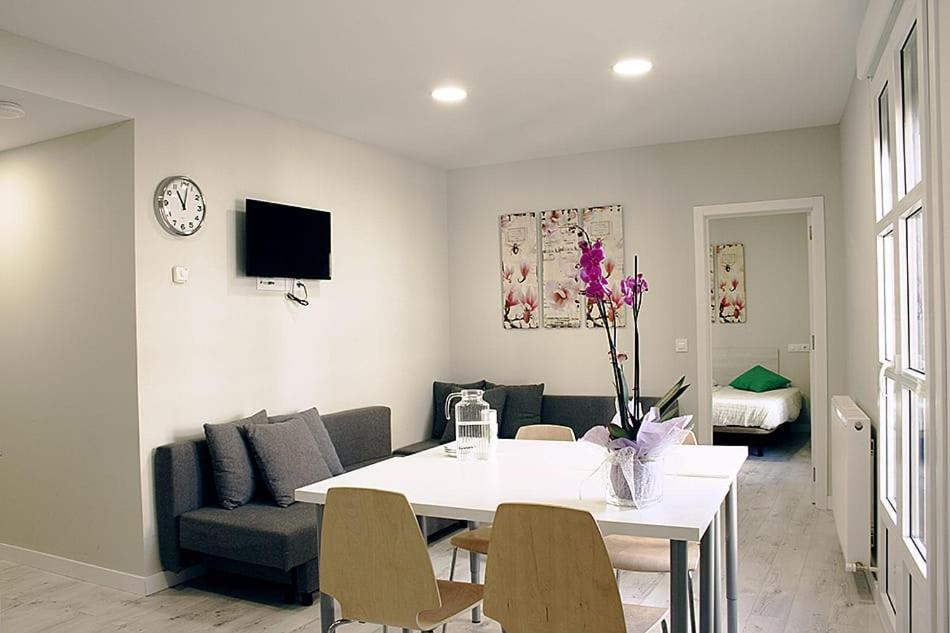 Apartamentos Logroño Centro في لوغرونيو: غرفة معيشة مع طاولة وكراسي بيضاء