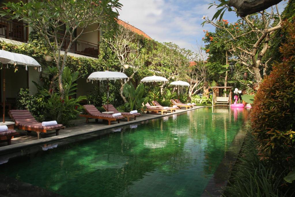 a pool at a resort with chairs and a swimming pool at Sapodilla Ubud in Ubud