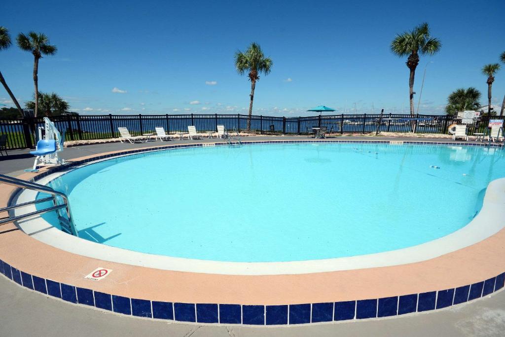 une grande piscine avec des chaises et des palmiers dans l'établissement Quality Inn & Suites on the Bay near Pensacola Beach, à Gulf Breeze