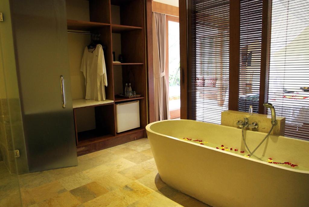 a bath tub in a bathroom with a window at Sapodilla Ubud in Ubud