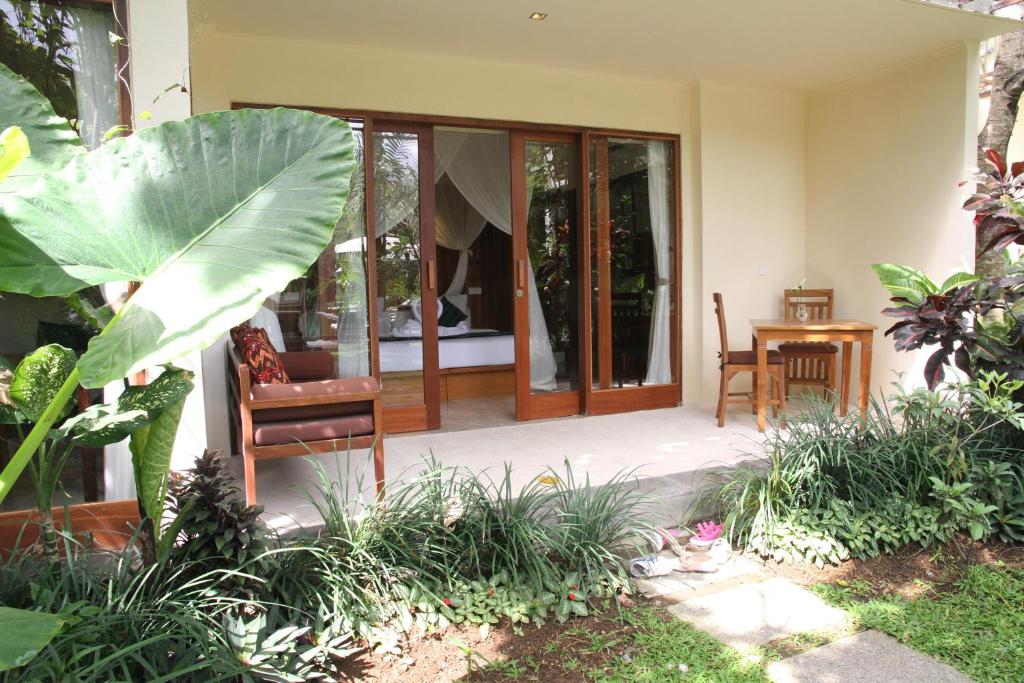 a porch of a house with a chair and a table at Sapodilla Ubud in Ubud