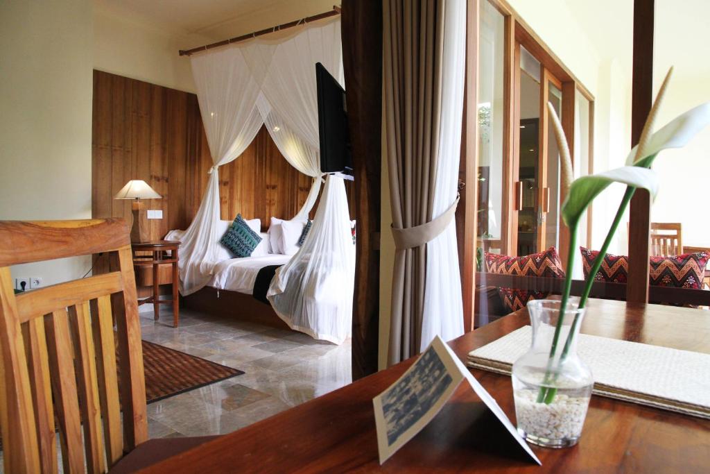 a hotel room with a bed and a desk with a table at Sapodilla Ubud in Ubud