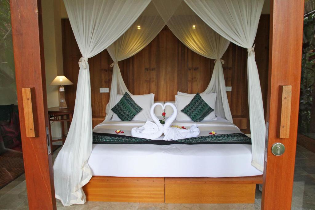a bed with two swans sitting on it at Sapodilla Ubud in Ubud