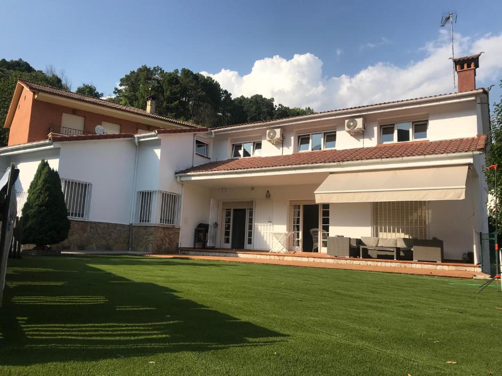 une maison blanche avec une grande pelouse devant elle dans l'établissement EL LLANO - El Hornillo, tu pueblo en la Sierra de Gredos., à El Hornillo