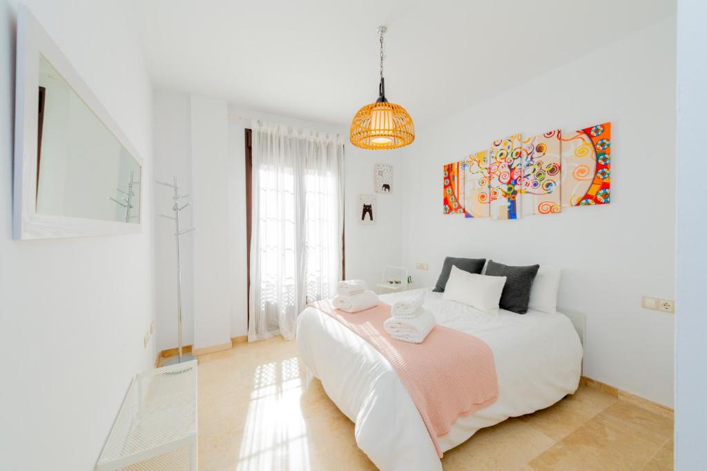 een witte slaapkamer met een bed en een hanglamp bij Apartamento Turístico La Vega in Antequera