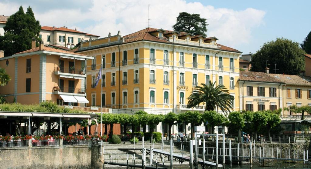 duży żółty budynek obok zbiornika wodnego w obiekcie Hotel Excelsior Splendide w mieście Bellagio