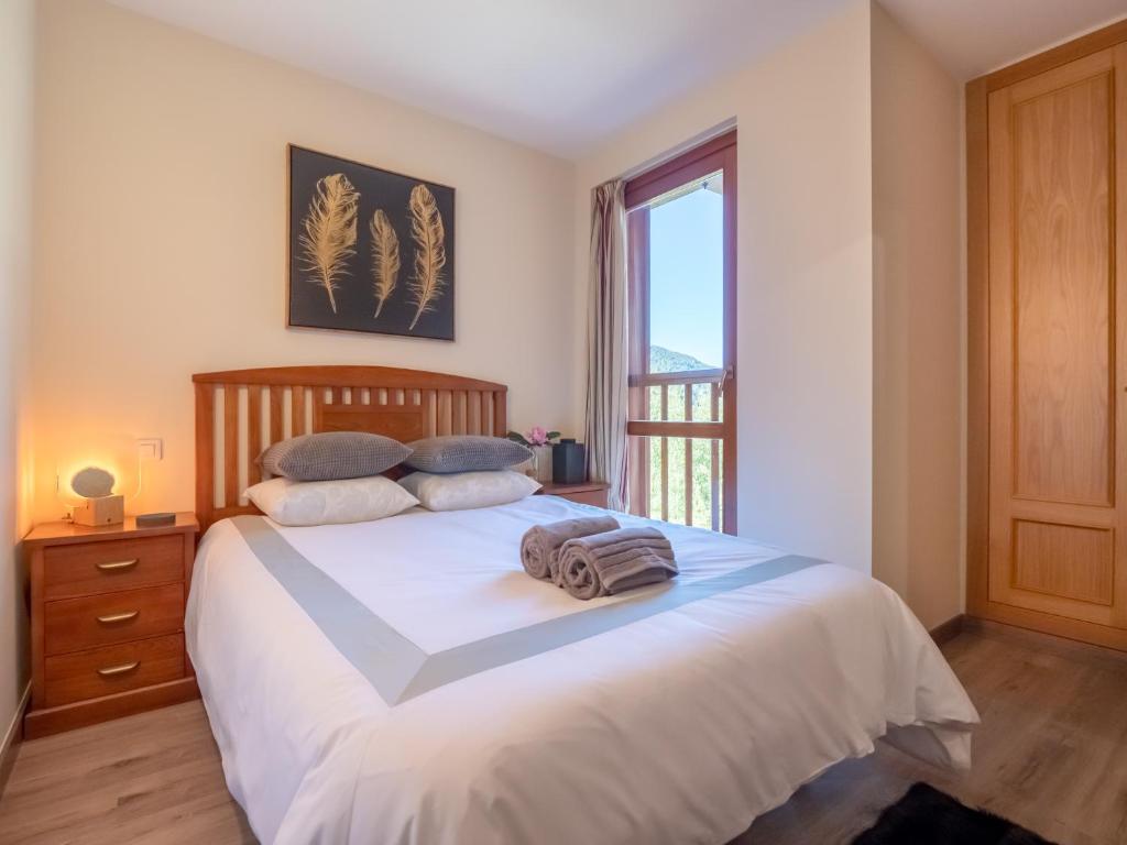 a bedroom with a large white bed with a window at SOLDEU cosy home in Soldeu