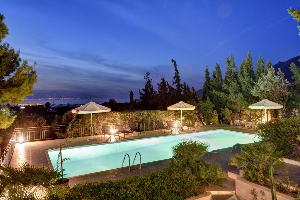 a swimming pool with lights and umbrellas in a yard at Villa Loutraki Sunset in Loutraki
