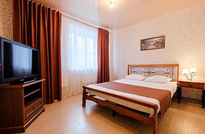 トムスクにあるДвухкомнатные апартаменты Советская 69のベッド1台、薄型テレビが備わるホテルルームです。