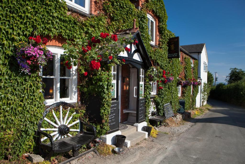 a building covered in ivy with a bench and flowers at The Golden Lion Inn in Denbigh