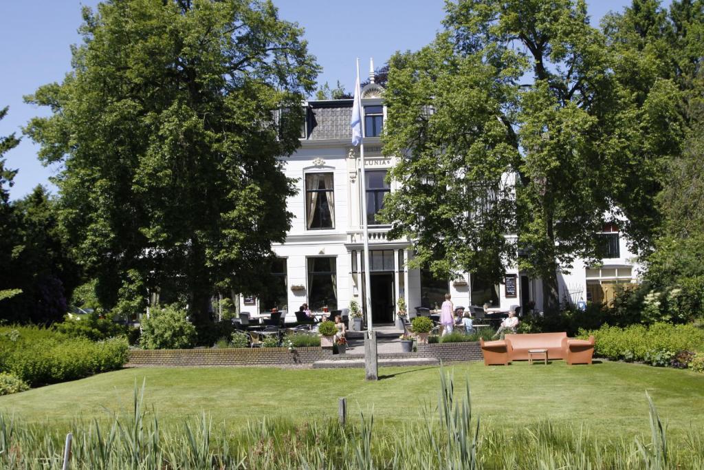 een wit huis met een gazon ervoor bij Hotel Restaurant Lunia in Oldeberkoop