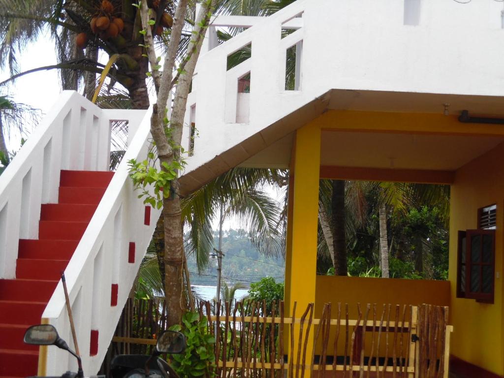 a house with a yellow and white wall and stairs at Allan Guest Mirissa in Bandaramulla
