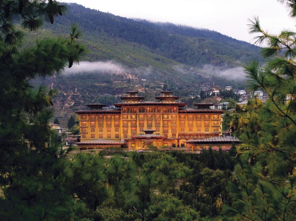 un gran edificio naranja en una colina con una montaña en Pemako, en Thimphu