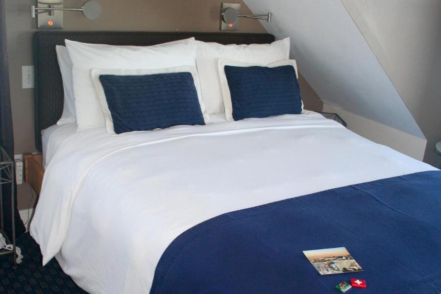 a large bed with blue and white sheets and pillows at Benchmark Inn in Provincetown