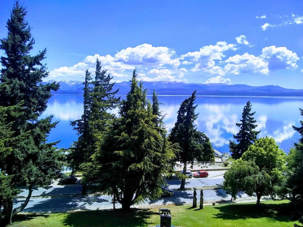 a view of a lake with trees in the foreground at Departamento Vista Huapi in San Carlos de Bariloche
