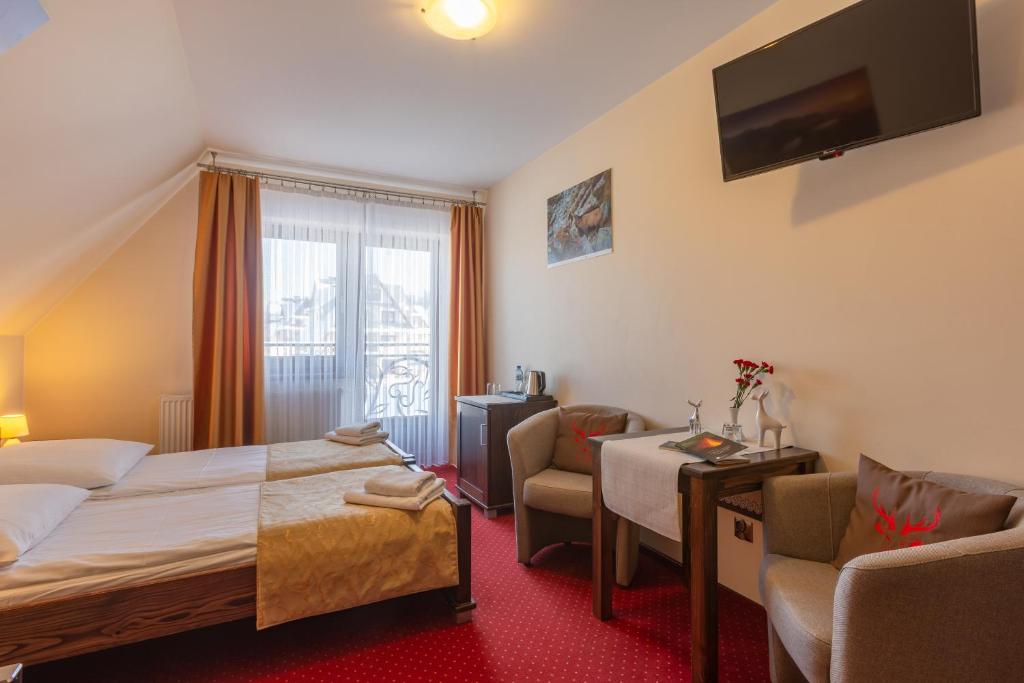 ザコパネにあるWilla Skalny Potokのベッドと椅子、窓が備わるホテルルームです。