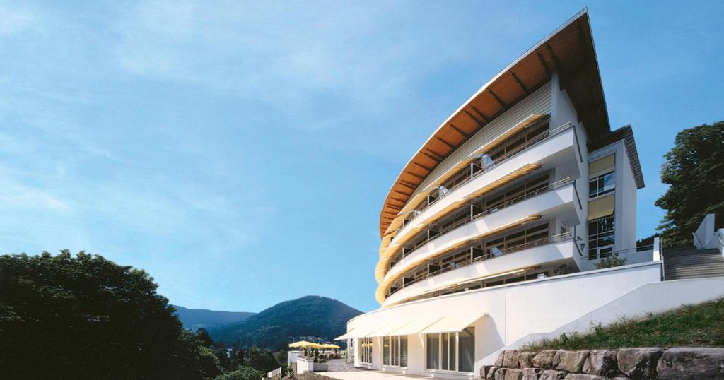 un edificio en una colina con montañas en el fondo en Schwarzwald Panorama, en Bad Herrenalb