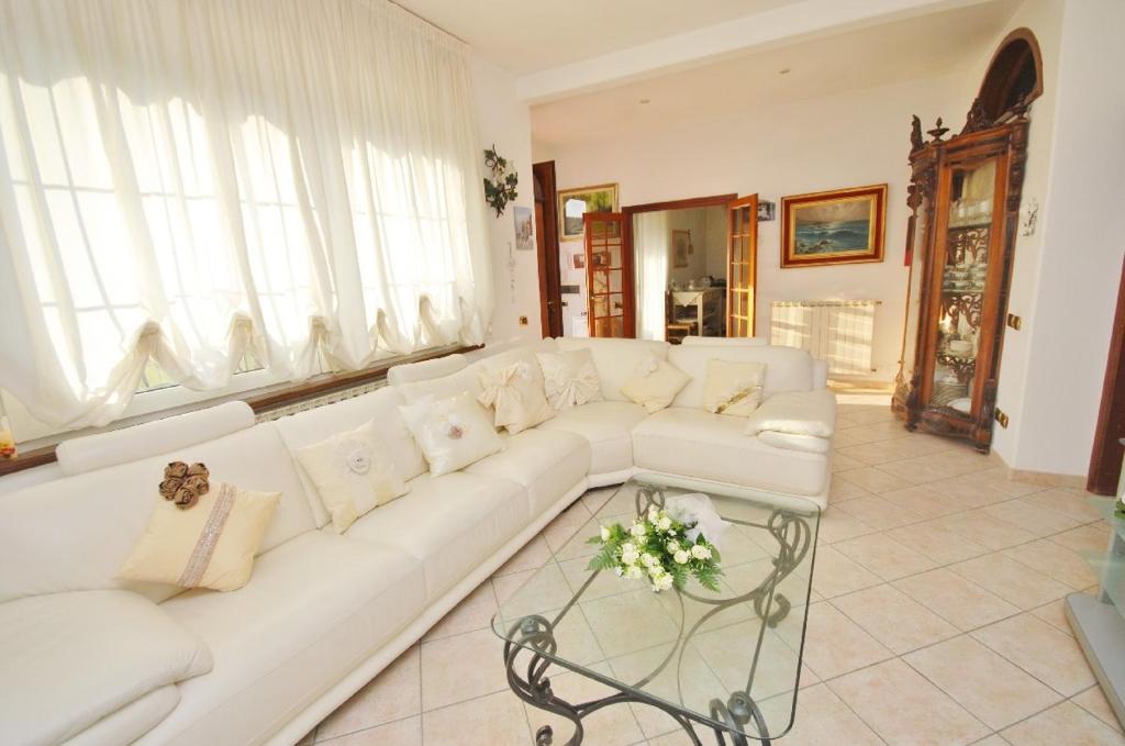 um sofá branco numa sala de estar com janelas em Raffinato attico vicino al mare con solarium Lido di Camaiore em Camaiore