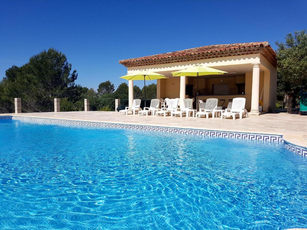 a pool with chairs and umbrellas next to a house at Villa Lavanda in Trans-en-Provence