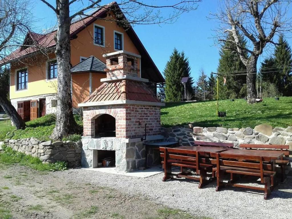 einem Backsteinofen mit einem Tisch und einer Bank vor einem Haus in der Unterkunft Vila Snjeguljica in Gorači