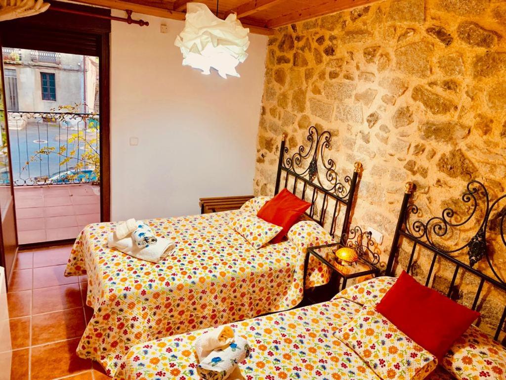 - une chambre avec 2 lits et un mur en pierre dans l'établissement Casa Rural el Comercio Sierra de Francia, à San Miguel de Valero