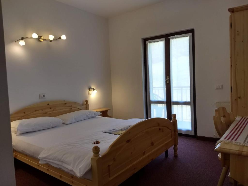 1 dormitorio con cama de madera y ventana grande en Hotel Ristorante Sassi Rossi en Taceno