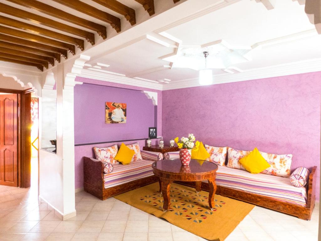 ein Wohnzimmer mit lilafarbenen Wänden, Sofas und einem Tisch in der Unterkunft Chez Ali Apartments in Essaouira